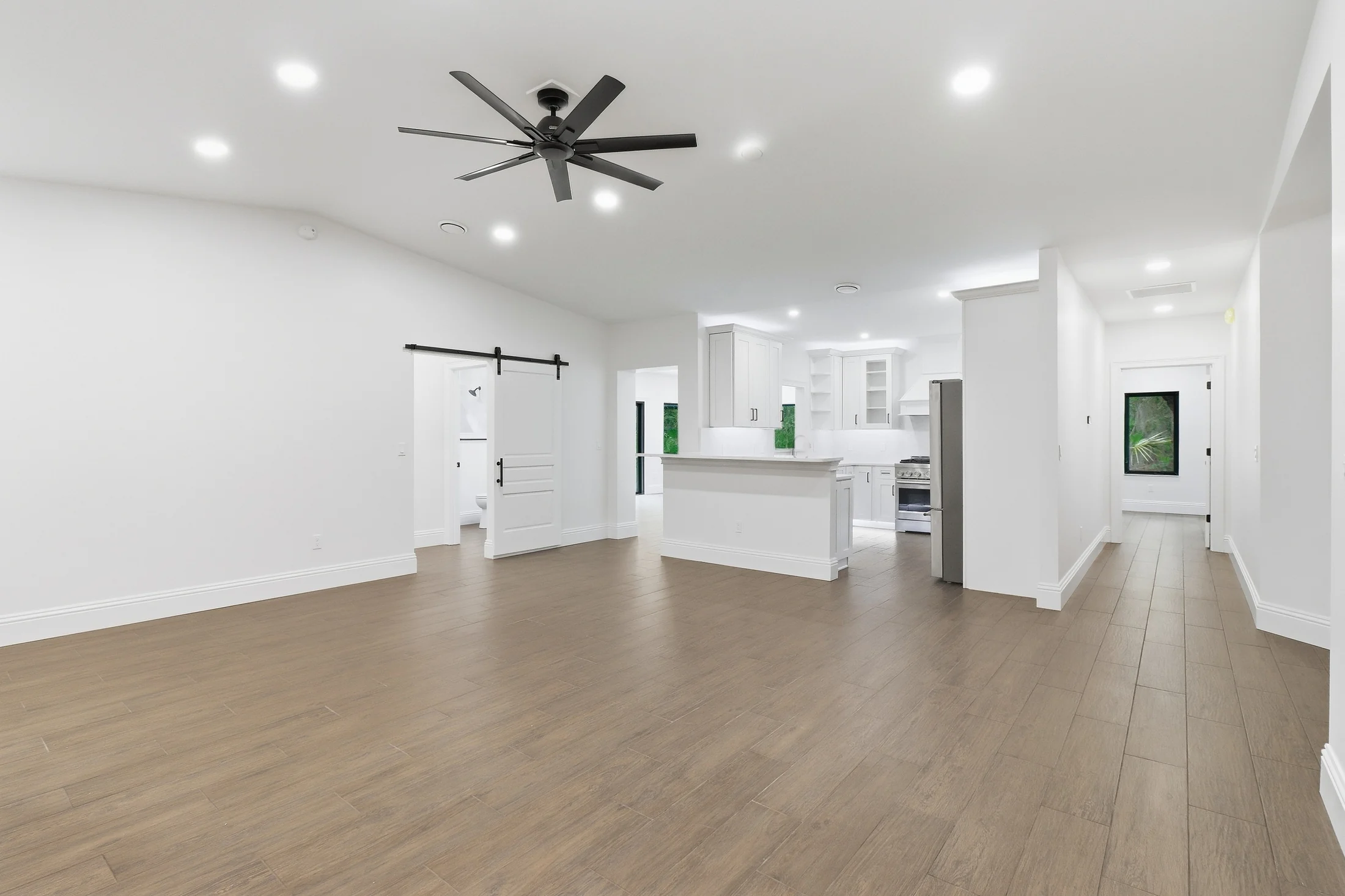 Open living room with wood floors and white kitchen